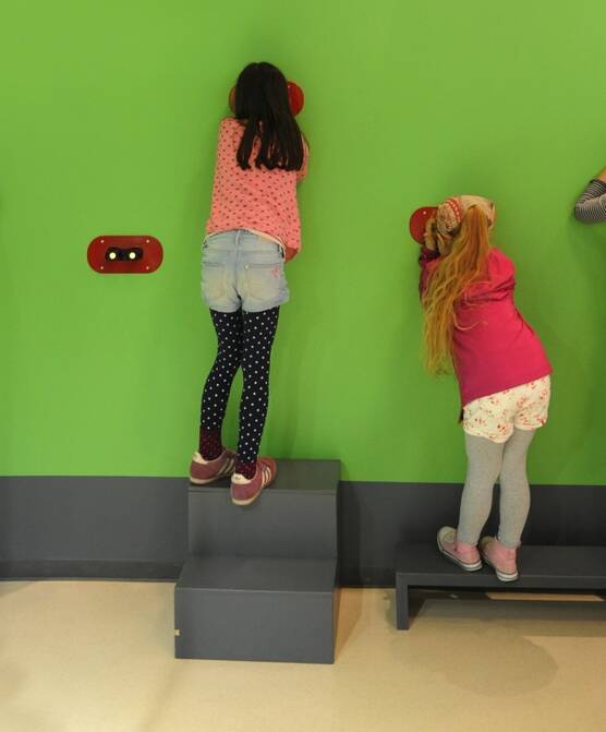 Kinder schauen durch Gucklöcher im Entdeckerzentrum der botanika