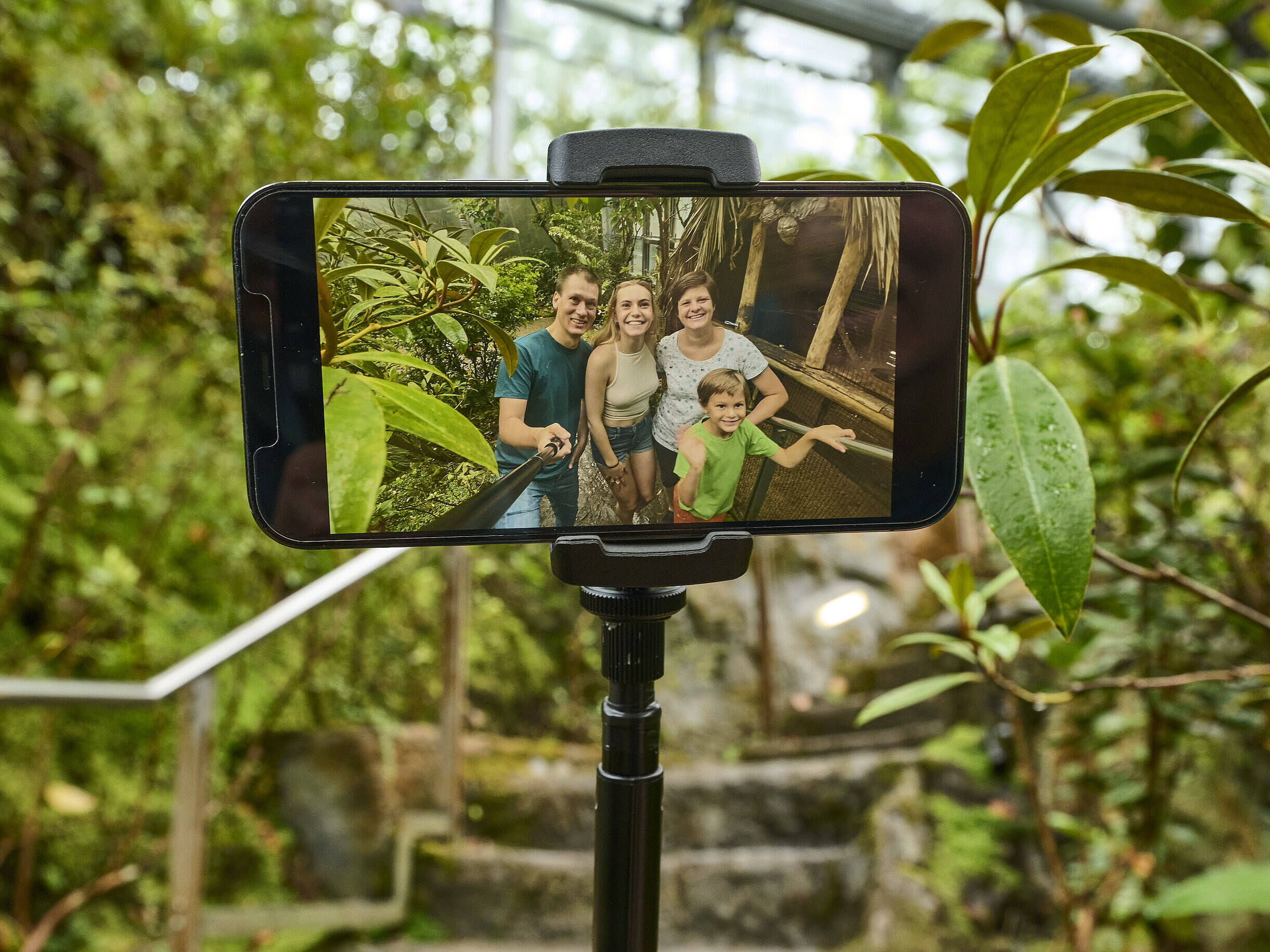 Handydisplay, das eine Familie zeigt, die gerade ein Selfie von sich in der botanika macht.