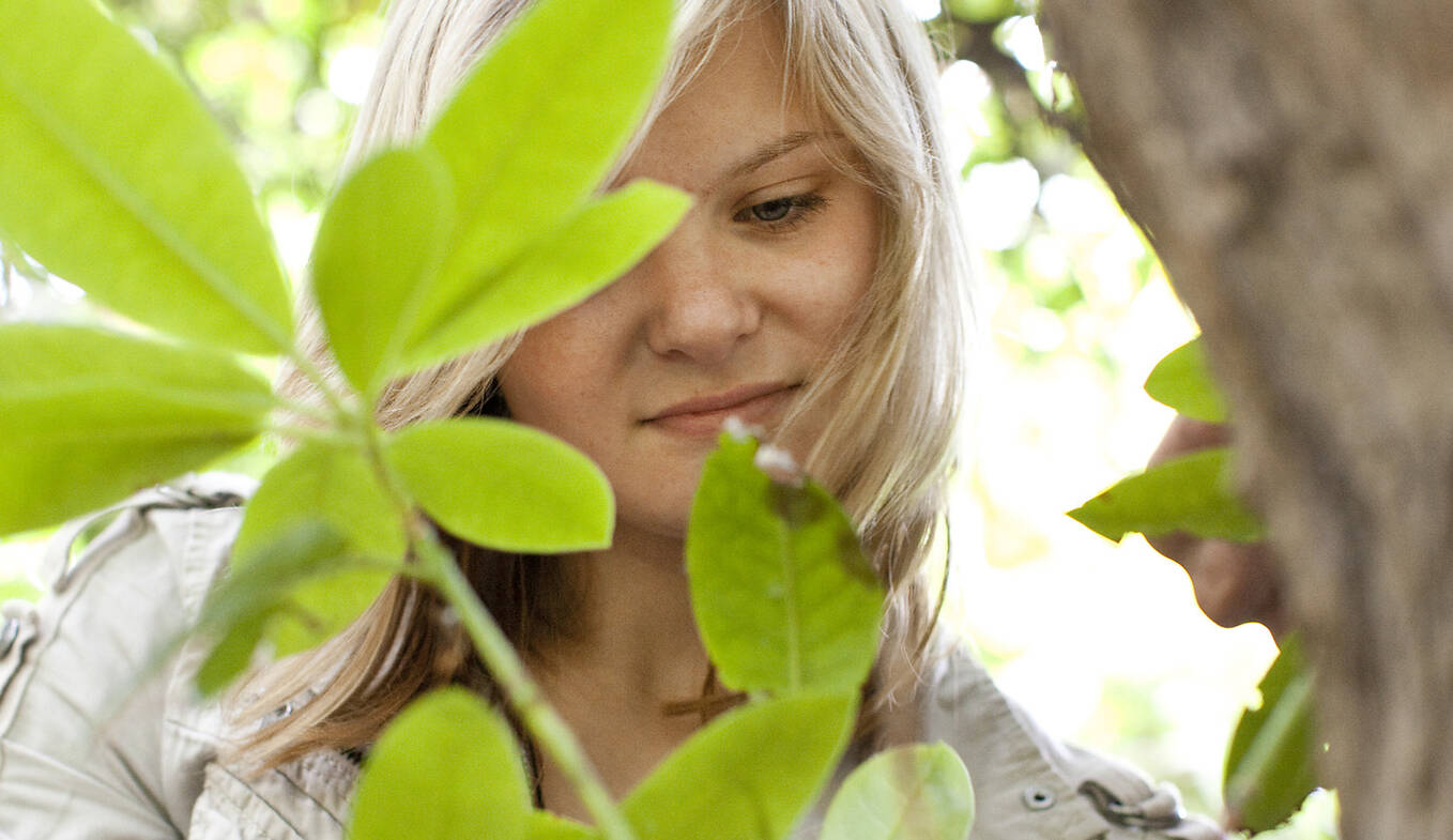 Junge Frau forscht und beobachtet Blätter im Außenbereich der botanika