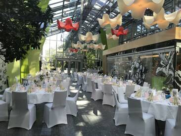 Feierlich dekorierte Banketttische für eine Hochzeitsfeier im Glasfoyer der botanika